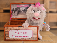 Stofftiermaus sitzt in Holzkiste